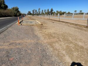 A fenced outdoor area with gravel and dry grass under a clear blue sky.