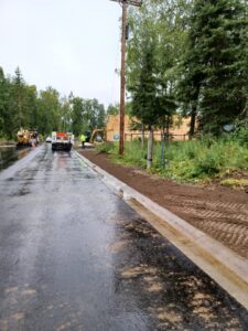 A freshly paved wet road with a truck driving away.