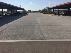 Empty parking lot with clear pavement and covered parking spaces on both sides.