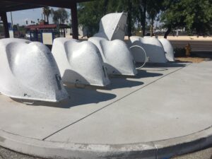 Large white whale sculptures displayed outdoors on a concrete platform.