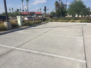 Empty parking lot with clear white lines under a blue sky.