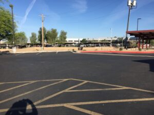 Empty parking lot with clear blue sky and a few trees in the background.