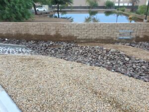 A landscaped garden area with gravel, rocks, and a low brick wall.