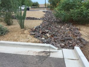 A rocky landscape edge beside a sidewalk curb.