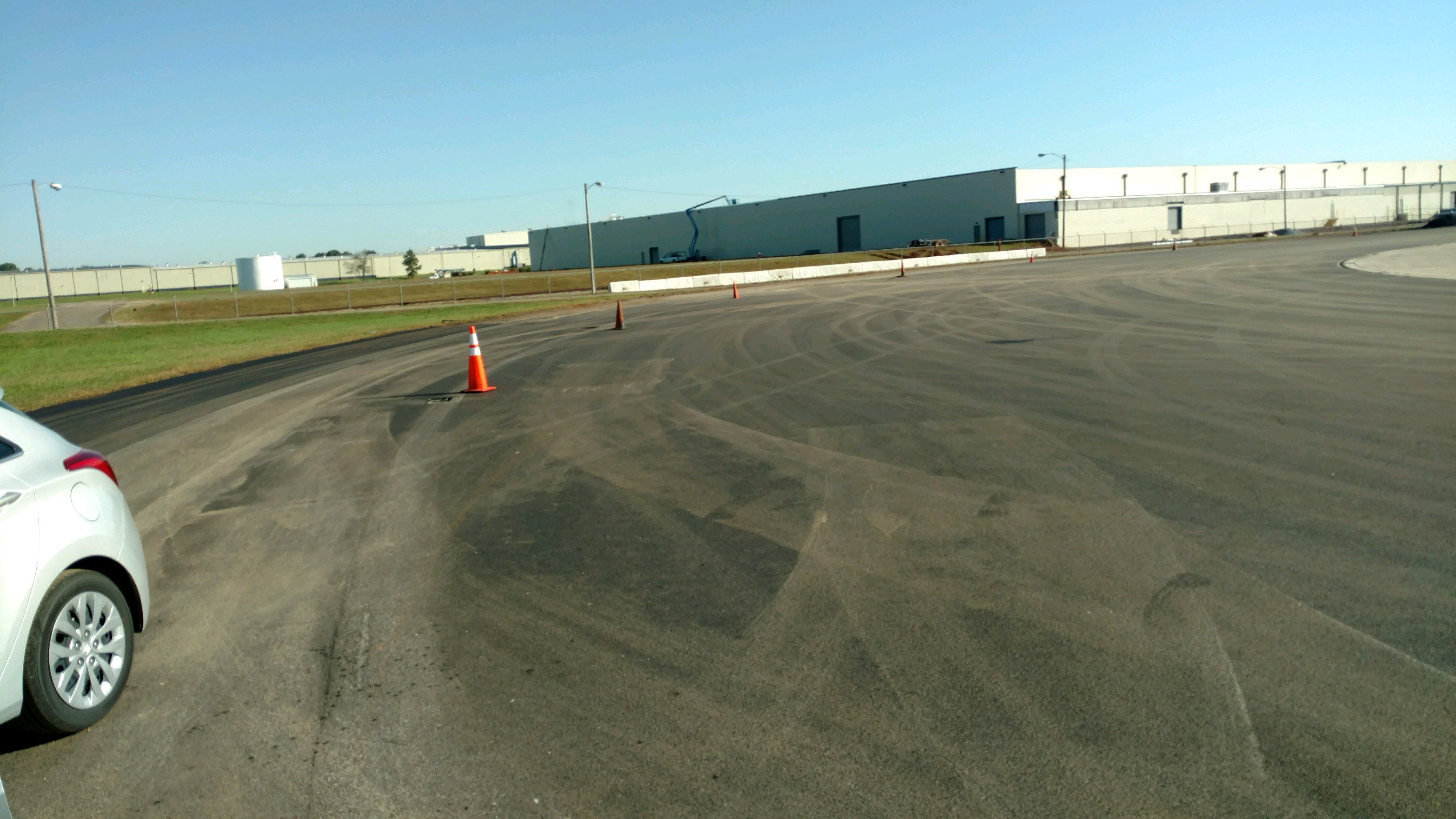 SUMITOMO 2 Empty parking lot with a single orange traffic cone under a clear blue sky.